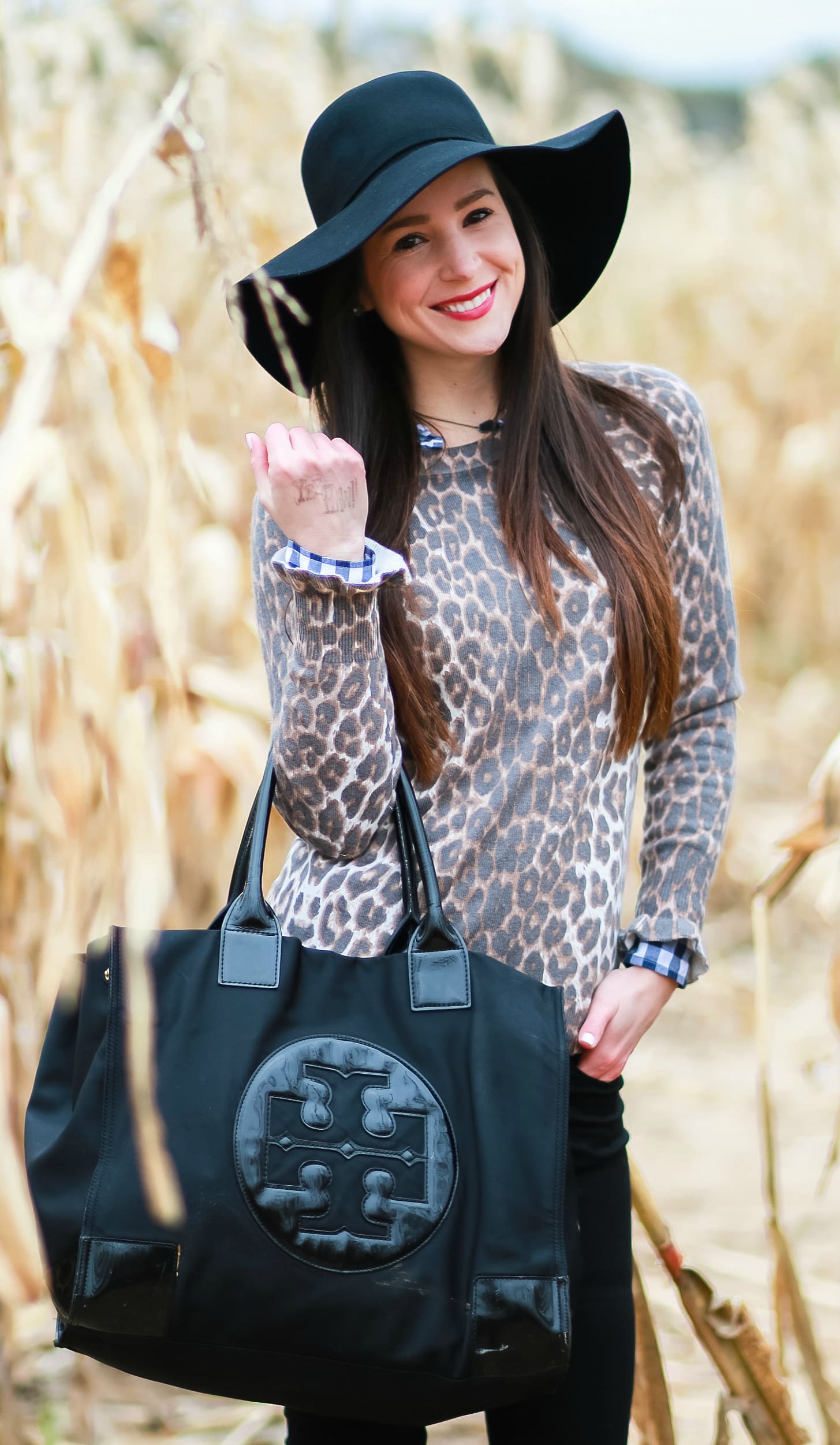 Black floppy hat with leopard crewneck sweater, J.Crew Factory blue gingham button down, black jeans, Nine West tall black boots, and a Tory Burch Ella tote | Comfy and casual fall outfit idea | How to wear a floppy hat in the fall by fashion blogger Stephanie Ziajka from Diary of a Debutante