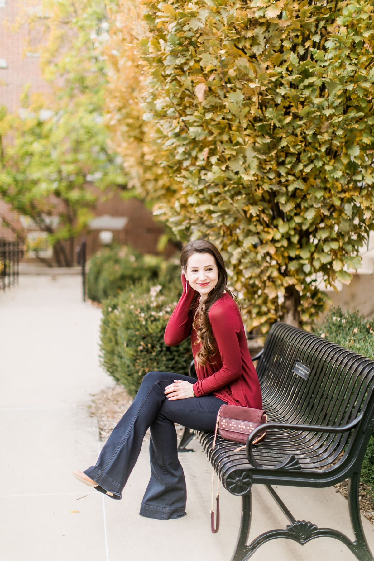 Long sleeve burgundy surplice top with dark wash flare jeans | Casual Thanksgiving outfit idea | What to Wear Out on Thanksgiving Eve by fashion blogger Stephanie Ziajka from Diary of a Debutante