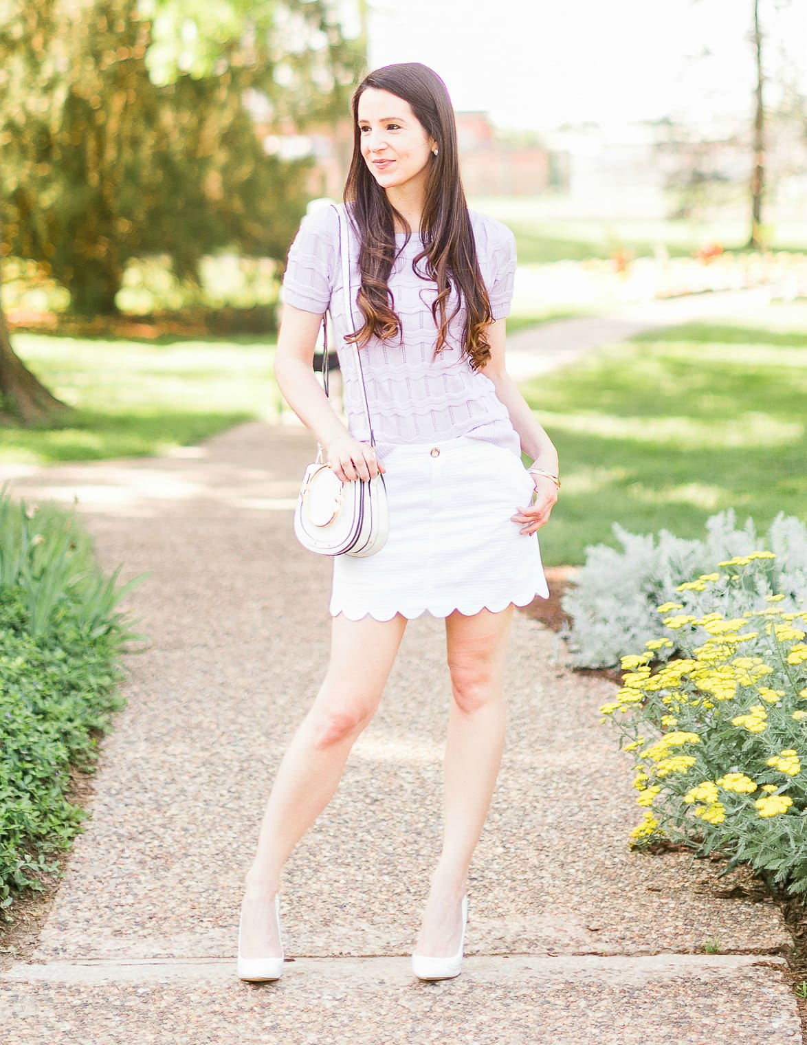 How to wear a short sleeve sweater in the spring by southern fashion blogger Stephanie Ziajka from Diary of a Debutante, lilac Cable Stitch short sleeve sweater, Lilly Pulitzer scalloped mini skirt, white Chloe Nile dupe bag, Chloe dupe bags, Kendra Scott mixed metal bangle set