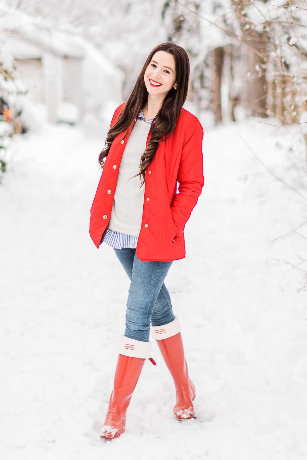 Preppy Winter Outfit: Red Quilted Jacket with Matching Red Hunter Boots by affordable fashion blogger Stephanie Ziajka from Diary of a Debutante, how to style red Hunter boots with tall welly boot socks, how to style a red quilted jacket, red quilted jacket styled with red tall Hunter boots, Hunter tall welly boot socks, a blue striped oxford, white crewneck sweater, and skinny jeans
