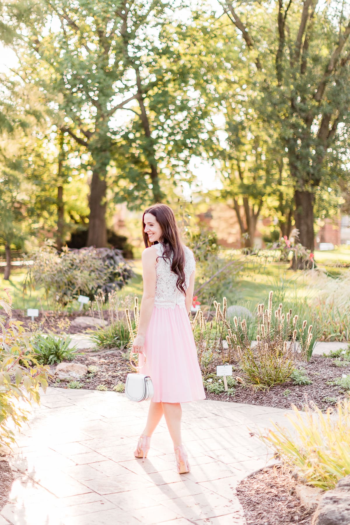 Day to Night: How to Wear a Pink Midi Skirt in the Fall by popular affordable fashion blogger Stephanie Ziajka on Diary of a Debutante, Amazon pink pleated midi skirt styled with an Amazon white lace crop top, white Chloe Nile dupe bag, and pink Nina Cherie dress pumps