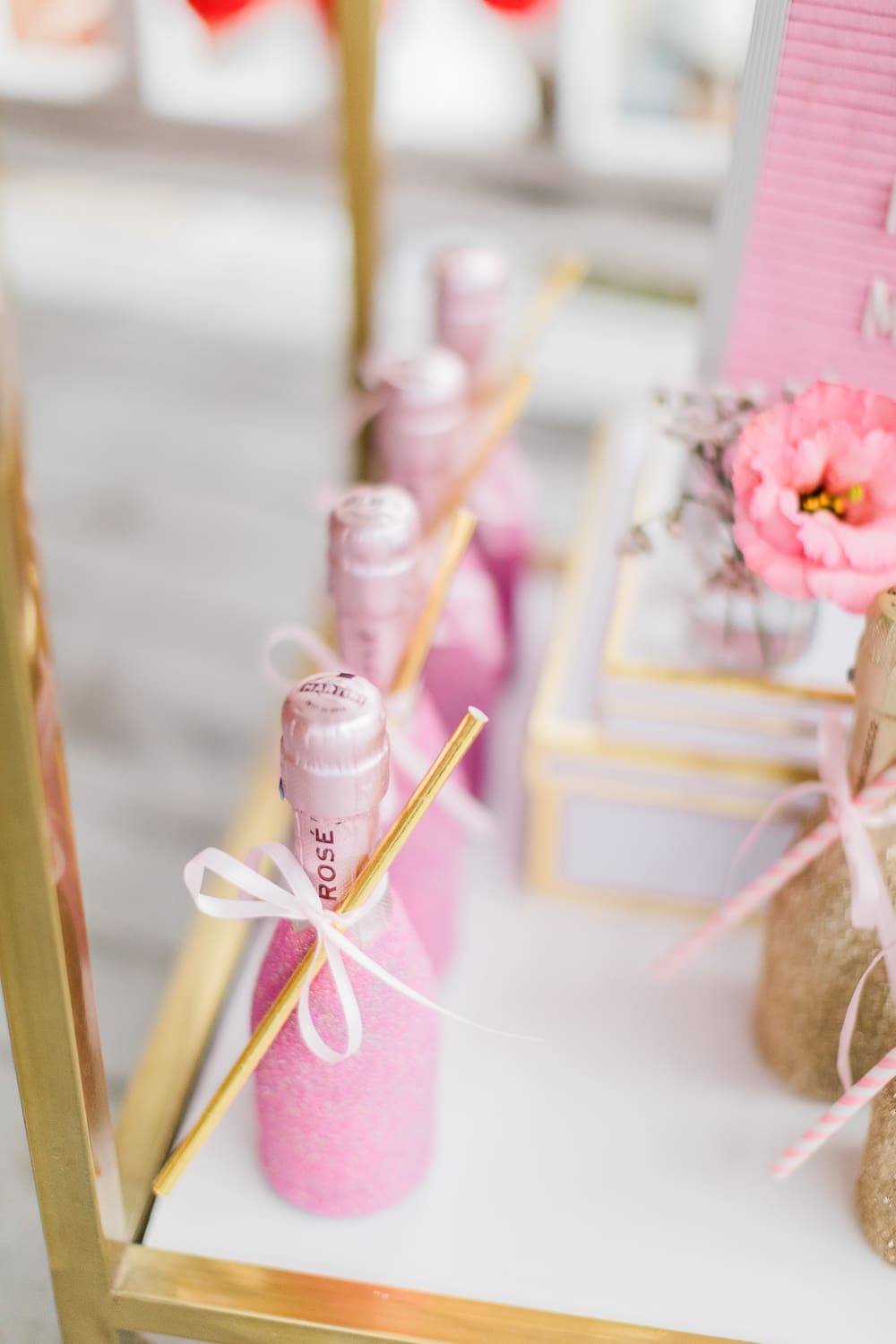 Pink glitter champagne splits displayed as party favors on southern lifestyle blogger Stephanie Ziajka's Galentine's Day bar cart